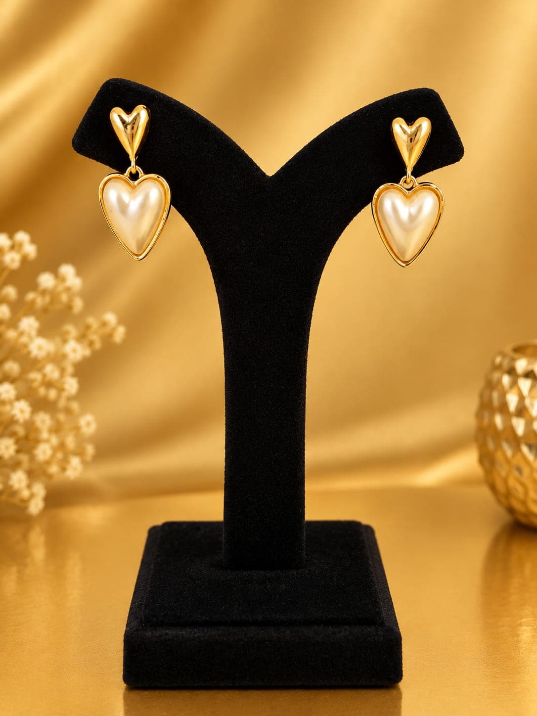 Gold-tone drop earrings displayed on a dark stand